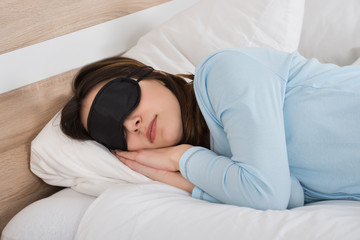 Fototapeta na wymiar Woman Sleeping With Eyemask On Bed