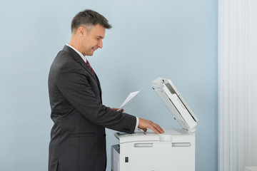 Businessman Using Photocopy Machine In Office