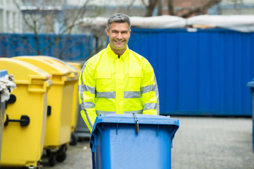Male Worker Walking With Dustbin On Street