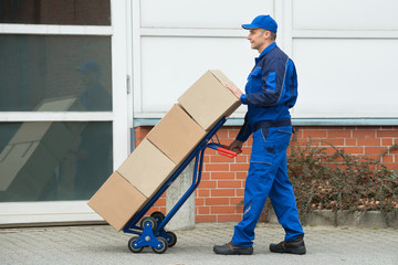 Delivery Man Carrying Boxes On A Hand Truck