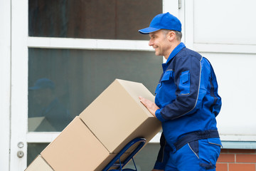 Delivery Man Carrying Boxes On A Hand Truck