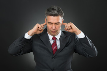 Businessman With Eyes Closed And Fingers In His Ears