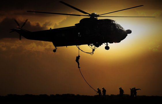 Helicopter dropping soldier during sunset