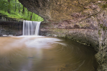 Viewed from beneath a large overhanging rock, whitewater plunges over Rock Rest Falls near Vernon, Indiana.