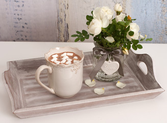 A tray with hot chocolate and white flowers of hedge rose