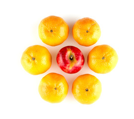 Oranges surrounding red apple arranged in flower shape against w
