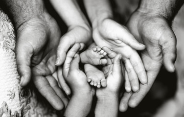 Руки отца, матери, дочери, держать ножки малыша. Дружелюбная счастливая семья, вместе (черно-белое фото)