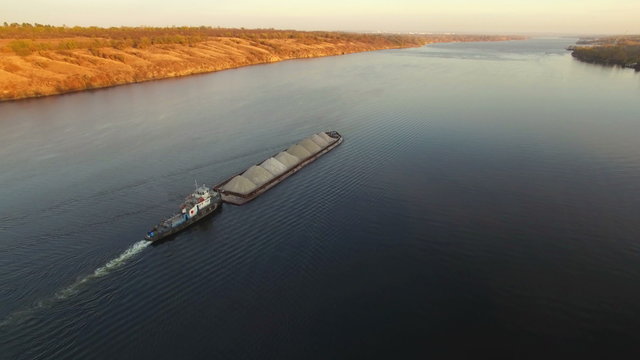 Aerial view of tug boat pushing barge of sand