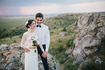 Beautiful wedding couple with bouquet flowers on the sunset