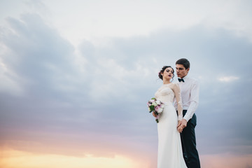 Beautiful wedding couple with bouquet flowers on the sunset