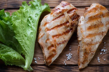 Close-up of grilled chicken breasts with fresh green salad