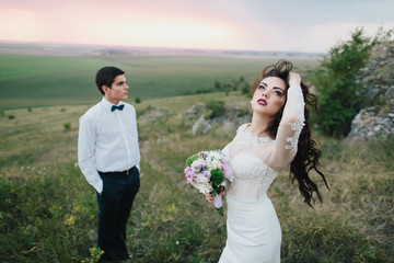 Beautiful wedding couple with bouquet flowers on the sunset