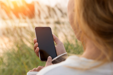 closeup woman using phone during sunset