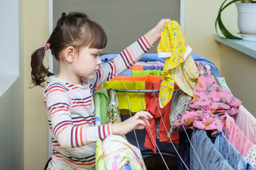 girl holding a laundered rompers and wants to hang him out to dr