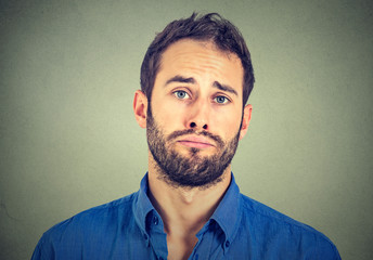 portrait of sad young man isolated on gray wall background