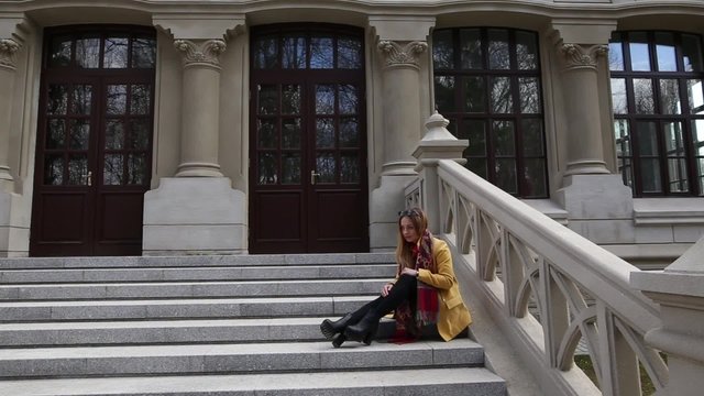Portrait of a young teenage girl sitting on the front stairs of the old building