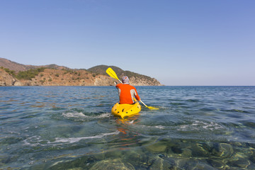 A man traveling by canoe along the coast in the summer.