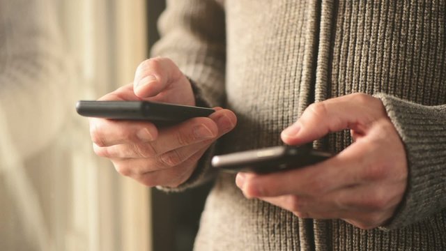 Smartphone mobile phone data synchronization, man syncing files and documents on personal wireless electronic devices at home.