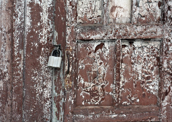 Grungy wooden door with padlock.