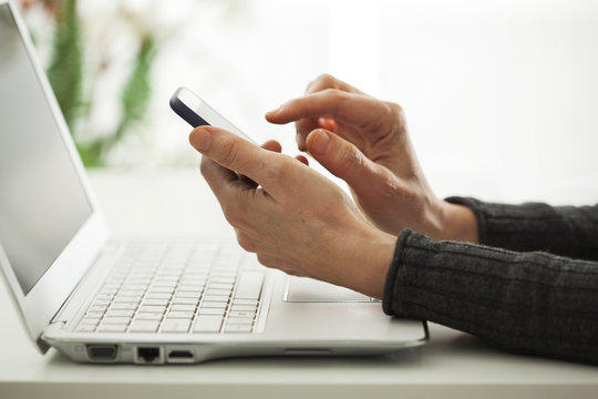 Close up hands using mobile phone and laptop