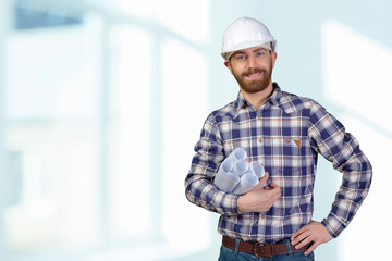 Young male engineer with helmet holding blueprints