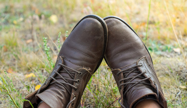 A pair of worn brown leather shoes over the countryside background