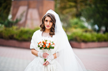 Portrait of charming curly bride in a fur coat