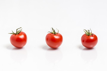 Three tomatoes in a row  isolated on white