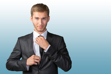 Young handsome businessman adjusting his tie