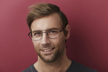 Obraz premium Smiling man in spectacles in red studio
