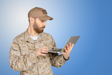 Portrait of young army soldier with a laptop