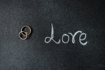 Fototapeta na wymiar Gold weddingng rings on the chalkboard