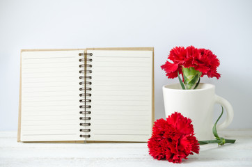 notepad and red Carnation flower