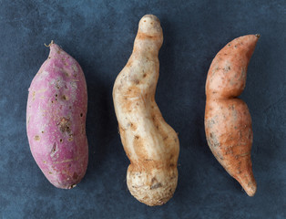Three kinds of sweet potatoes on grunge surface. Top view.