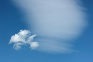 Two different clouds against blue sky.