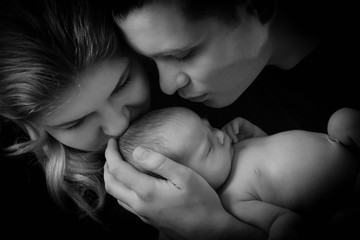 happy family , young parents holding a newborn baby in her arms and gently hugged him, black and...