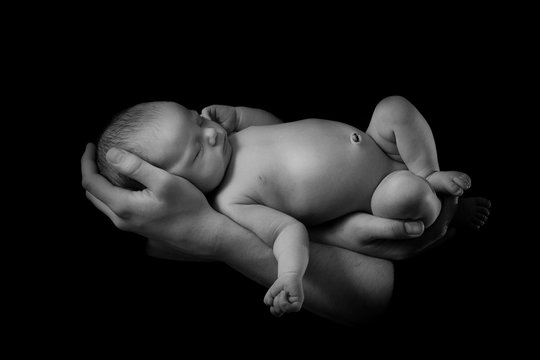 happy family , young parents holding a newborn baby in her arms and gently hugged him, black and white photo on a black background .