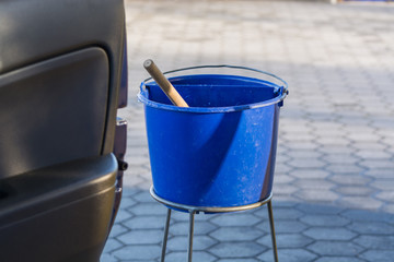 Blauer Eimer mit Wasser an einer Tankstelle