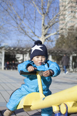 Cute Chinese baby boy playing seesaw outdoors