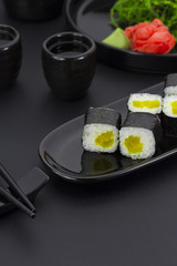 Vegetarian sushi roll with daikon ginger wasabi and chuka salad over black background