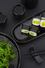 Vegetarian sushi roll with daikon over black background