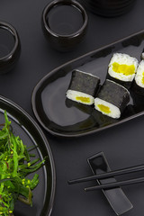Vegetarian sushi roll with daikon over black background