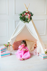 Little girl in pink dress near wigwam