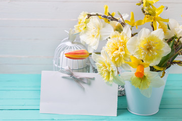Yellow daffodils, tulip flowers, candle in decorative bird cage