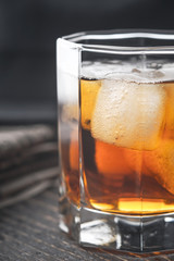 Whiskey with ice on the wooden table vertical