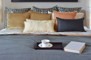 Fototapeta na wymiar modern bedroom interior with teacup on decorative wooden tray and white book on the bed