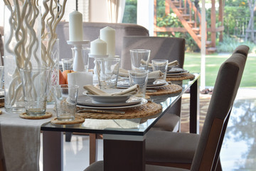 dining wooden table and comfortable chairs in modern home with elegant table setting