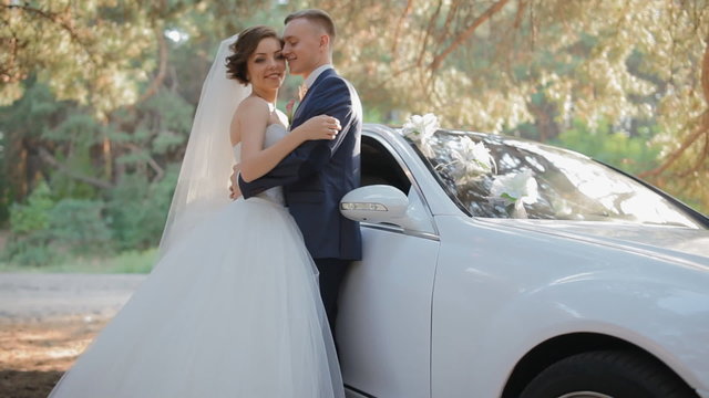 Bride and groom pose near the car
