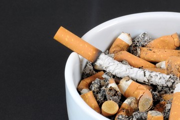 White ceramic ashtray detail full of smokes cigarettes