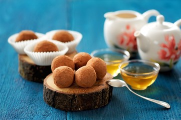 Homemade sweets in cocoa powder on oak board with tea and teapot